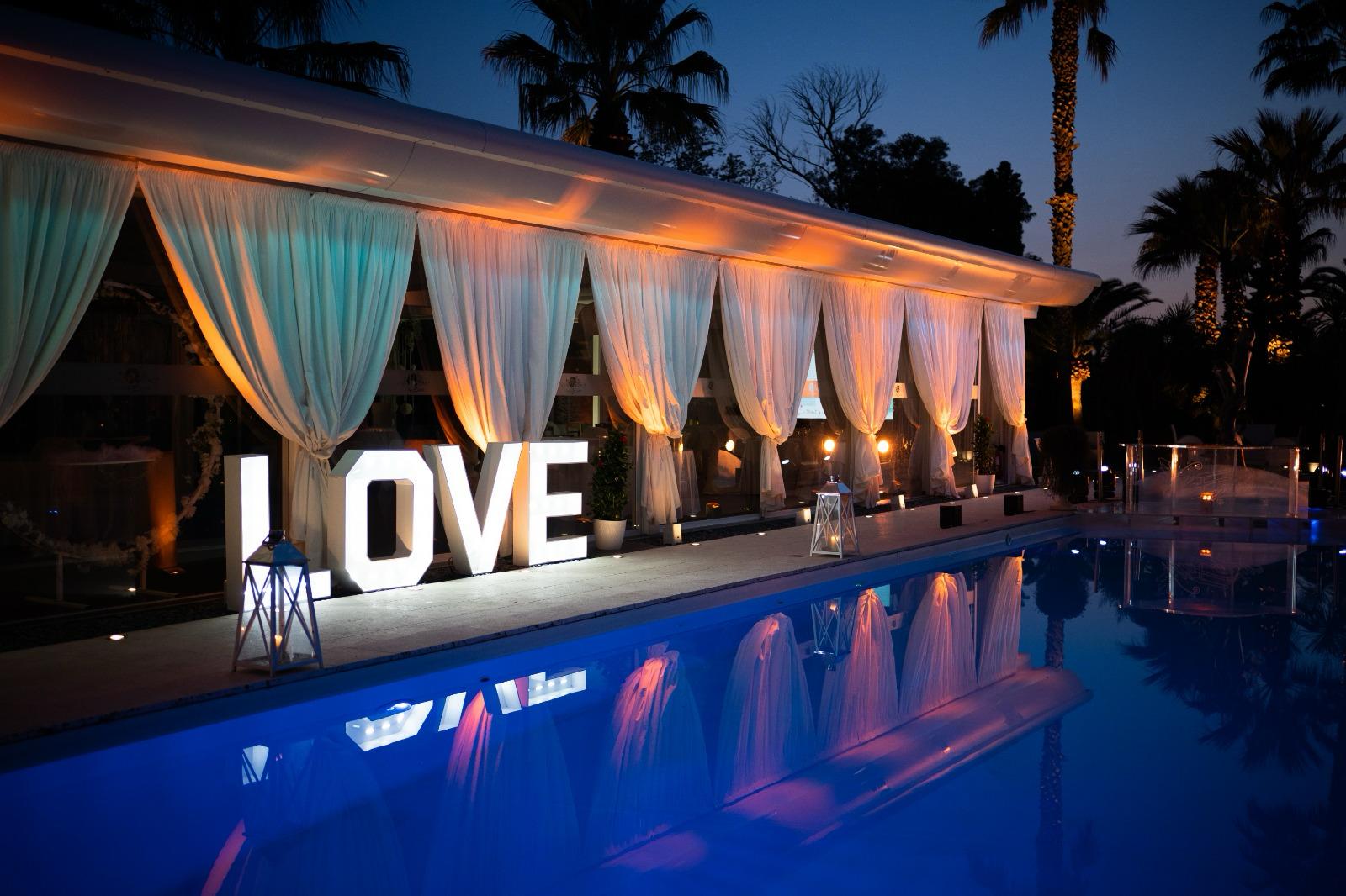 Villa Egidio di sera: scritta luminosa LOVE a bordo piscina